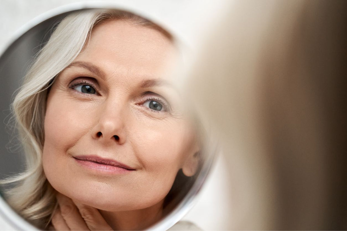 Mature woman looking at her skin in a mirror