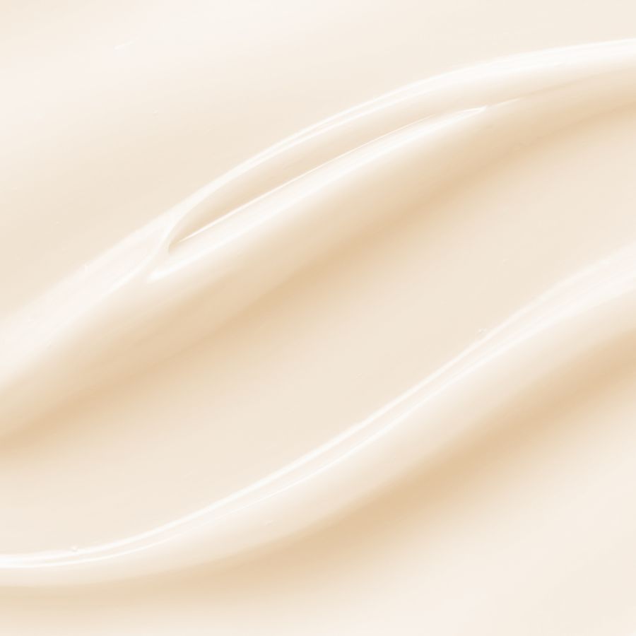 A close-up of a smooth, creamy off-white cosmetic texture with soft flowing ridges and a glossy finish.